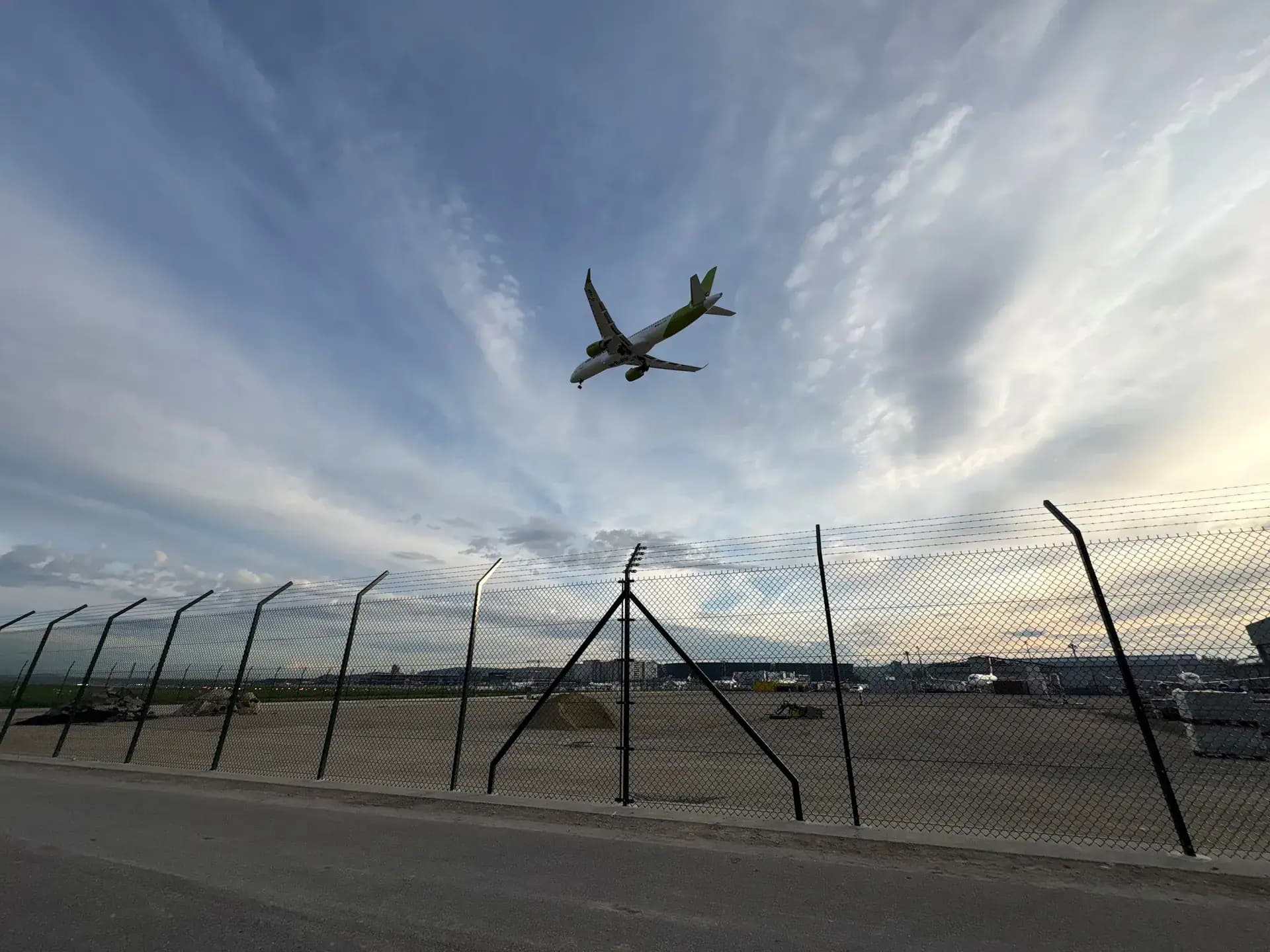 Flugzeug im Anflug über dem Flughafenzaun der Zone West