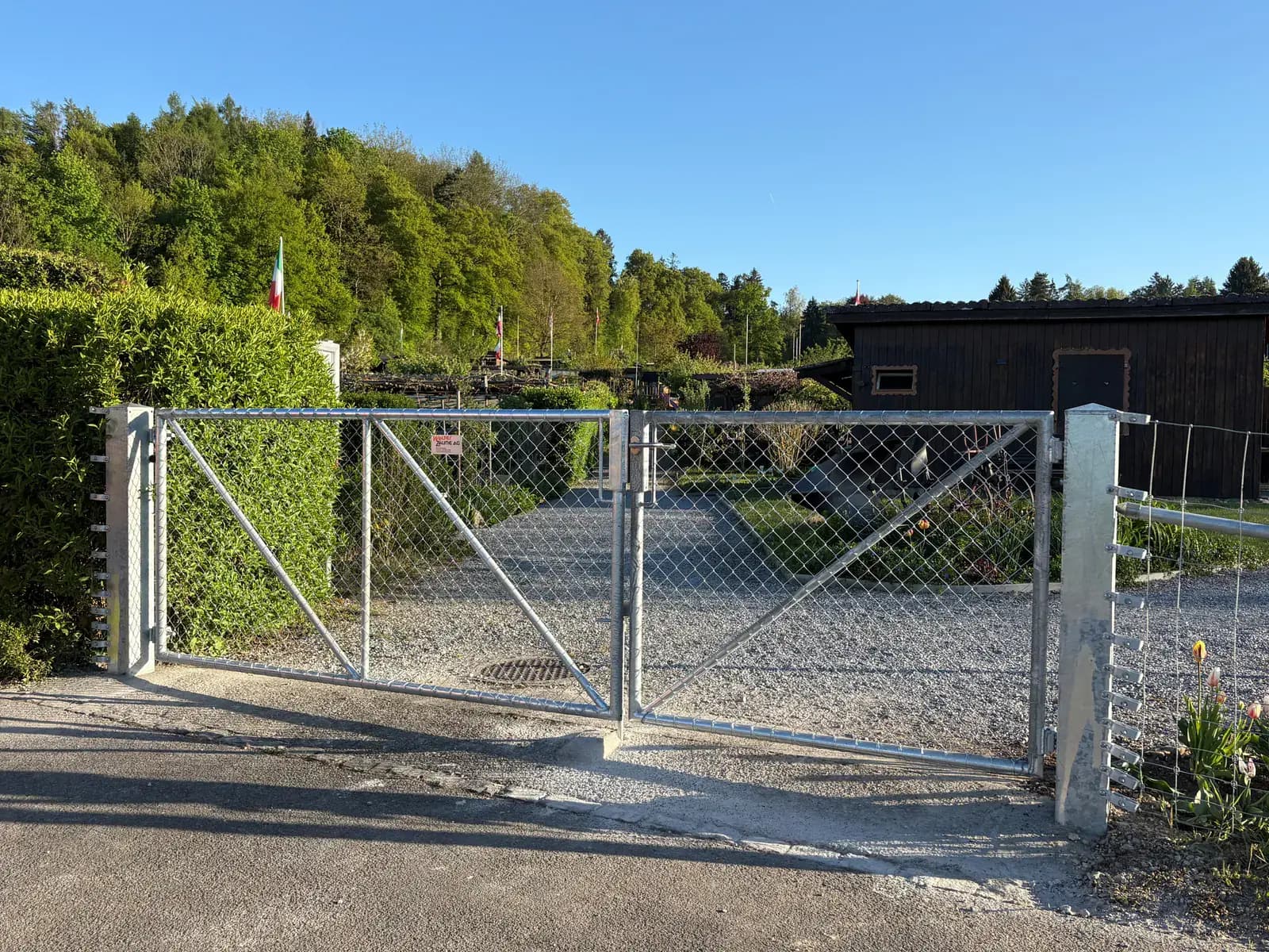 Zweiflügliges Metalltor mit Diagonalgeflecht an einer Grundstückseinfahrt