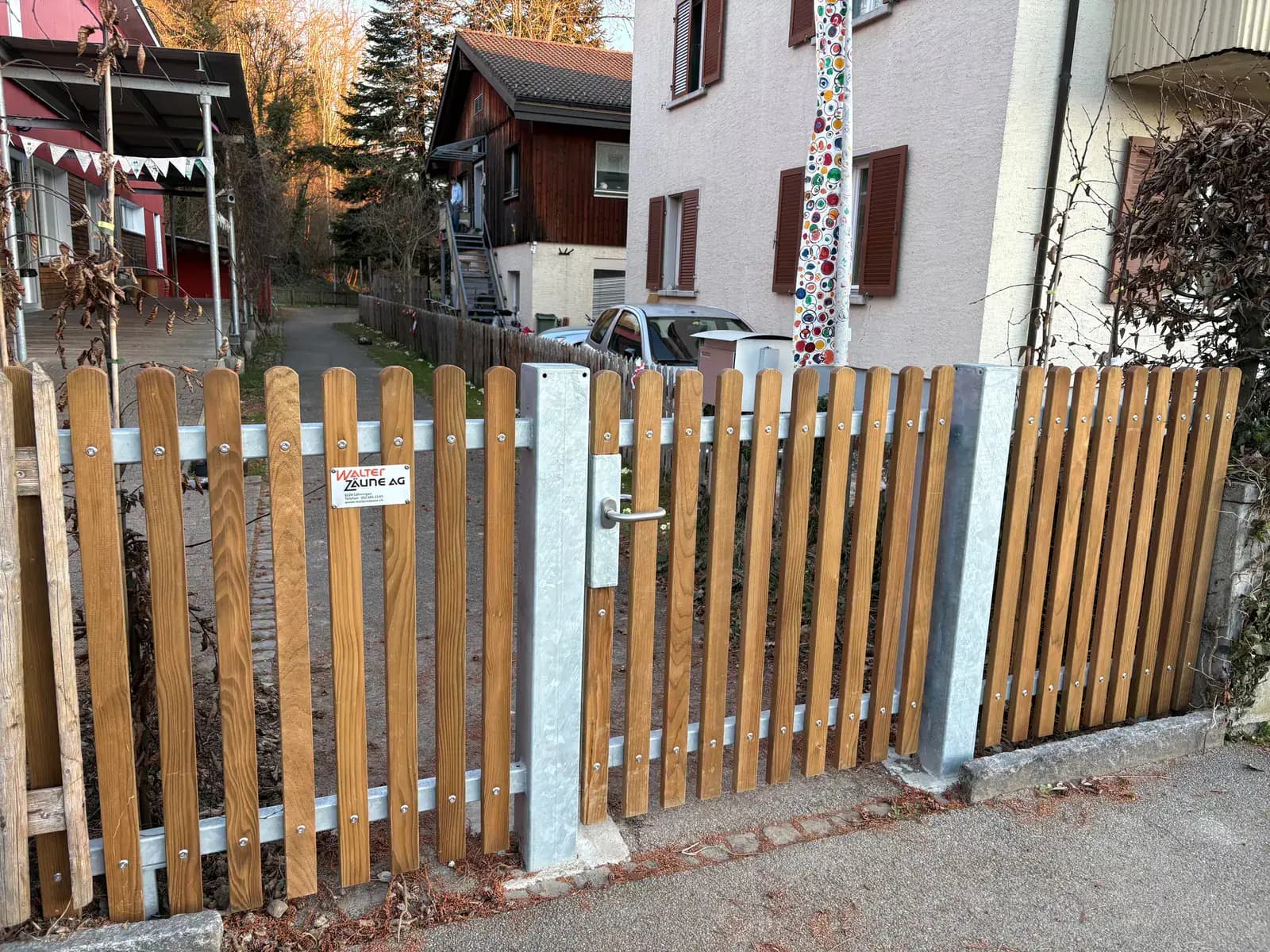 Holzzaun mit verzinktem Metalltor als Gartenzugang